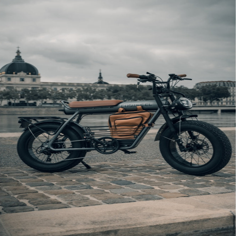 Motorcycle with thick tires on a cobblestone street in an urban setting.