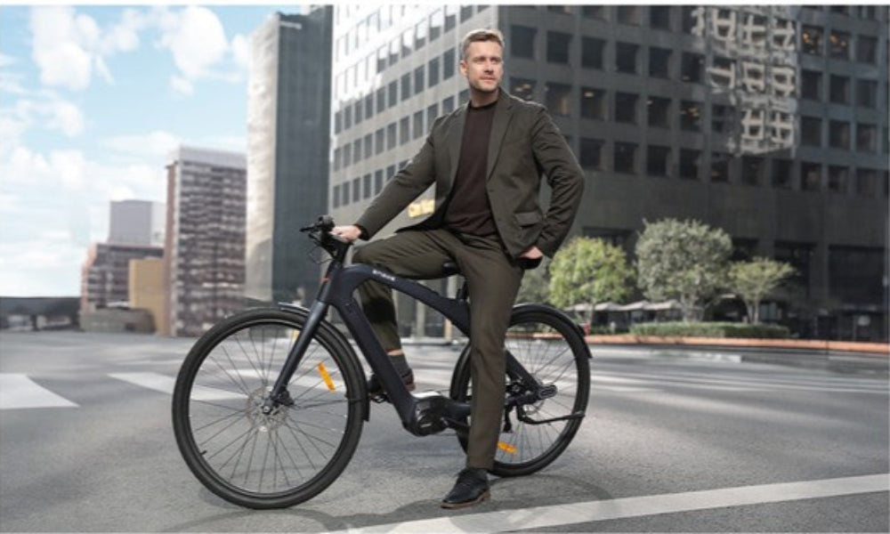 Man sitting on a bicycle in an urban setting with buildings in the background