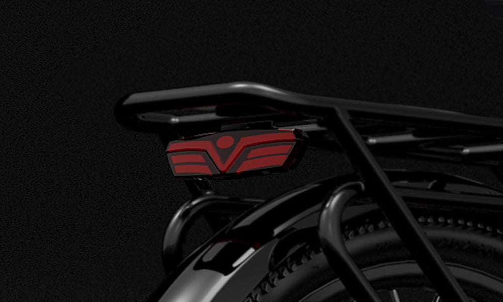 Close-up of a black motorcycle exhaust with a red logo on a dark background
