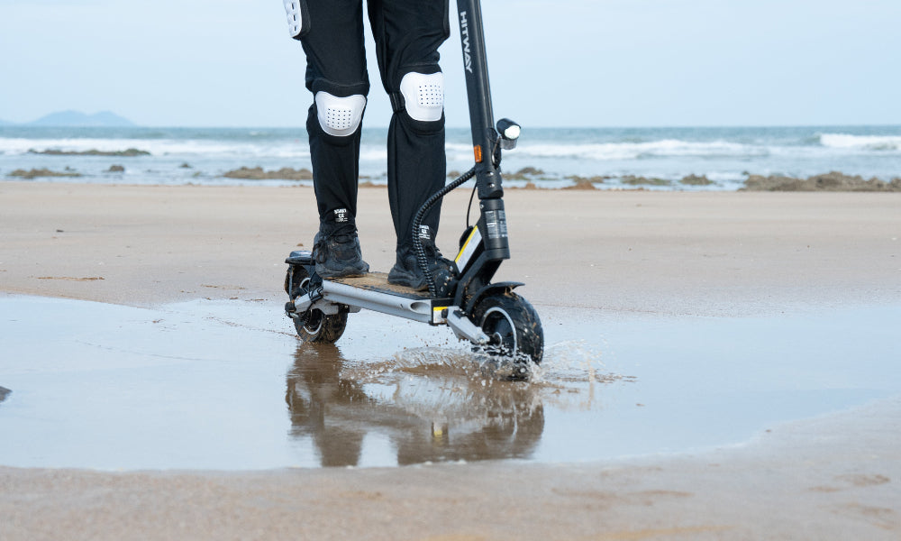 Person riding a scooter on a beach with ocean in the background
