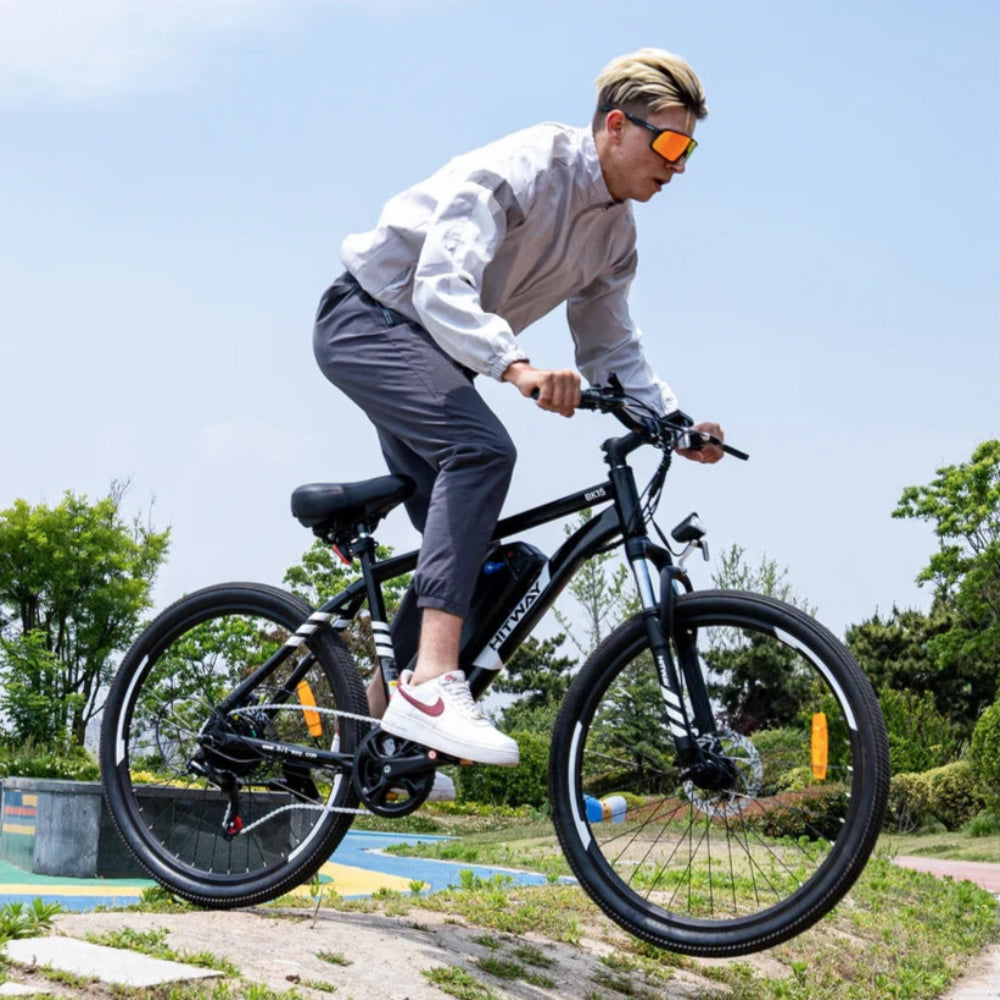 Person riding a black electric bike outdoors on a sunny day