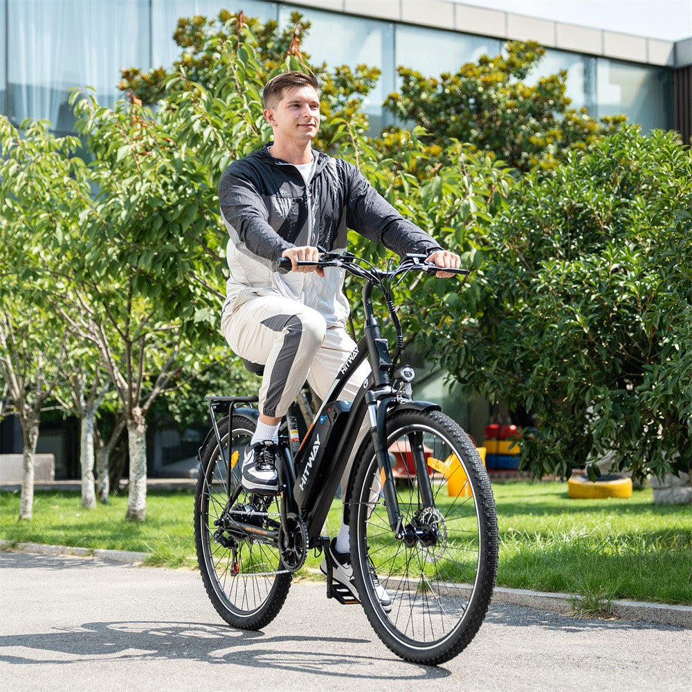 Man riding an electric bike outdoors with greenery and a building in the background