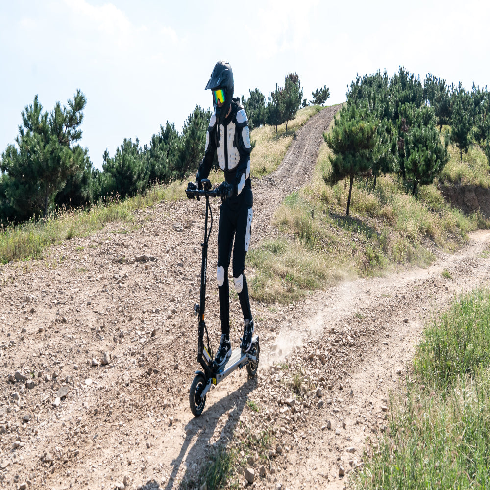 Person riding an electric scooter on a dirt path with trees in the background