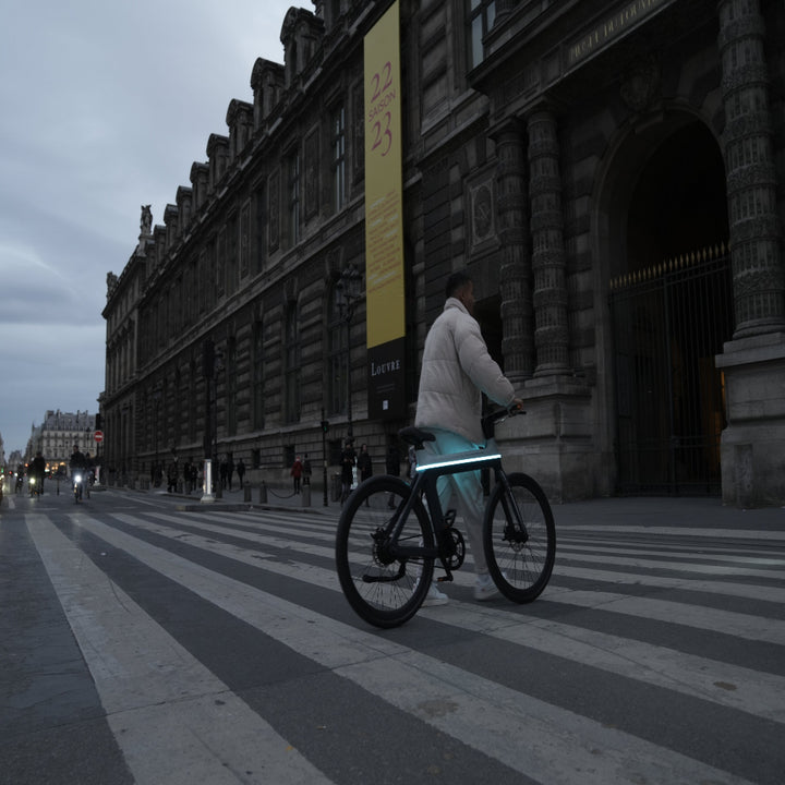 Person riding a bicycle on a city street with a large building in the background