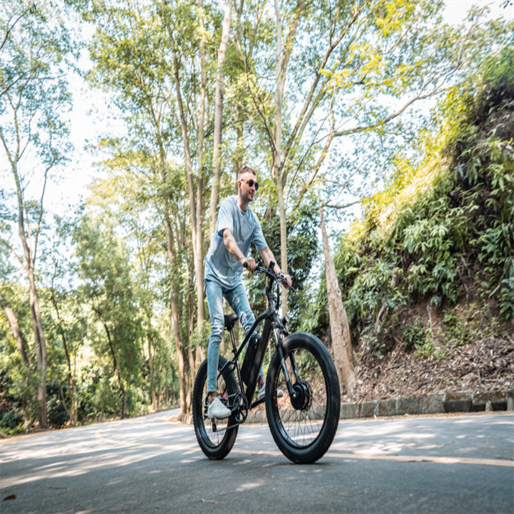 Man riding an electric bike on a tree-lined road