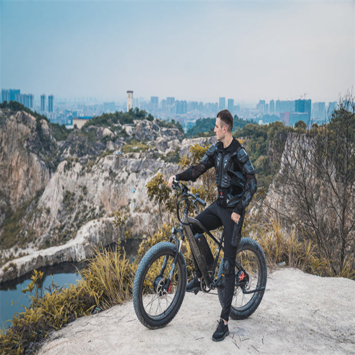 Man with electric bike on a mountain top with cityscape in the background