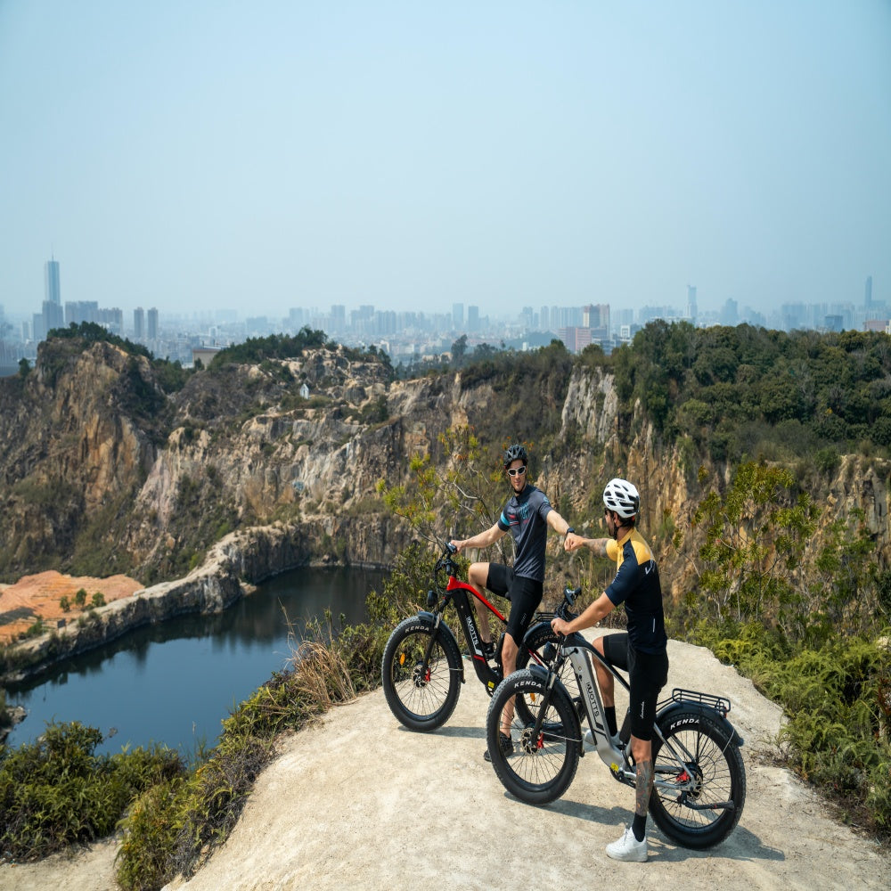 Two people with bicycles on a cliff overlooking a cityscape
