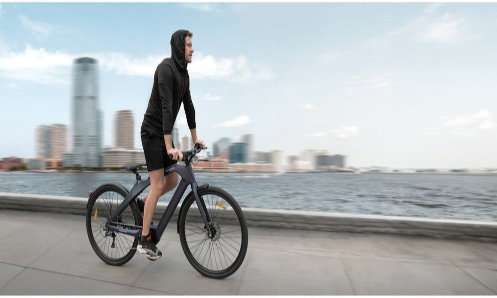 Person riding a bicycle on a path with a city skyline in the background