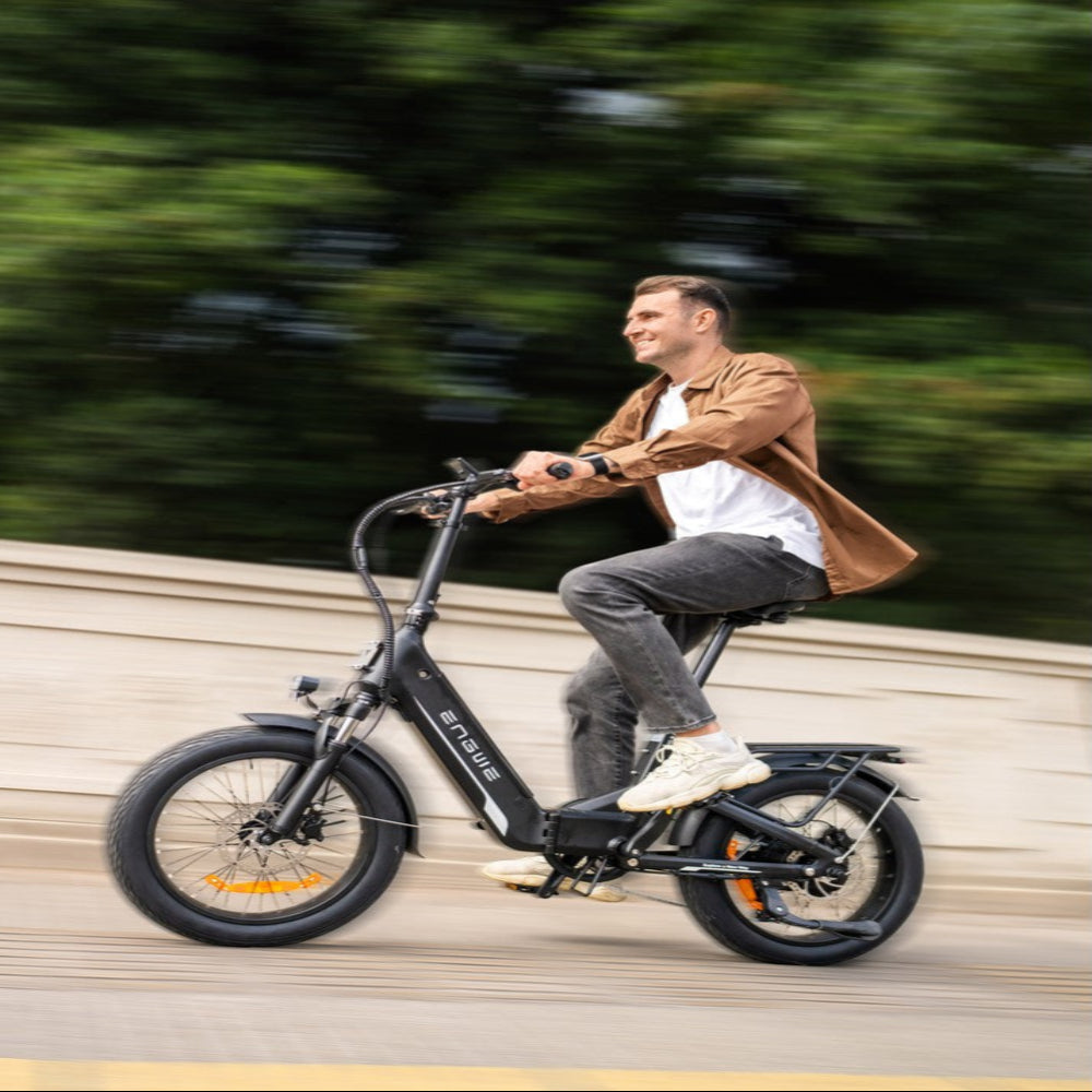 Man riding a black electric bike on a path with greenery in the background
