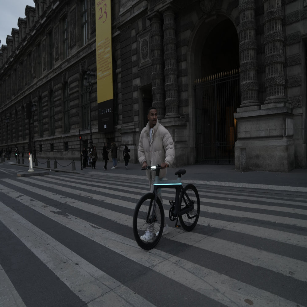 Person with a bicycle on a city street in front of a large building