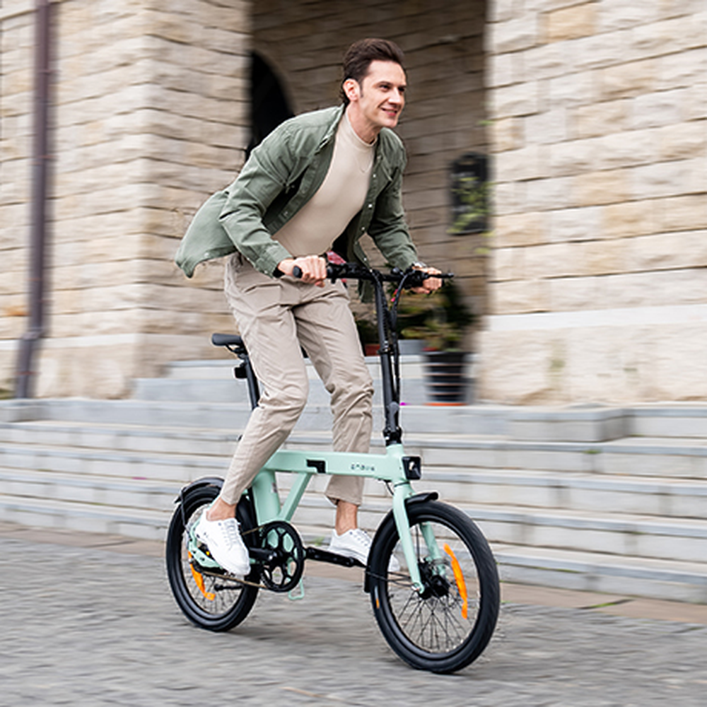 Man rijdt op een lichtgroene elektrische fiets in een stadsstraat.