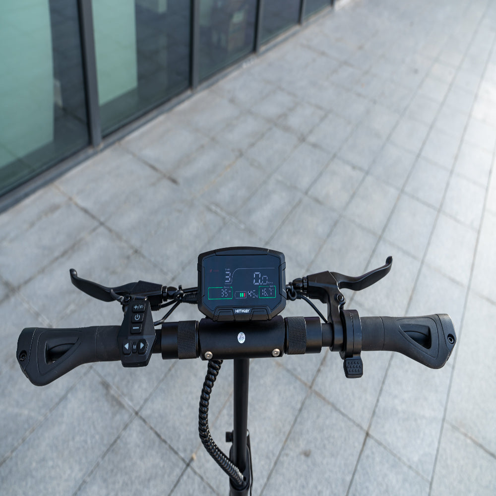 Close-up of an electric scooter handlebar with a digital display on a pavement.
