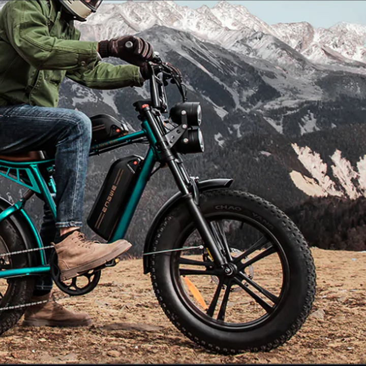 Person riding a green electric bike with mountains in the background