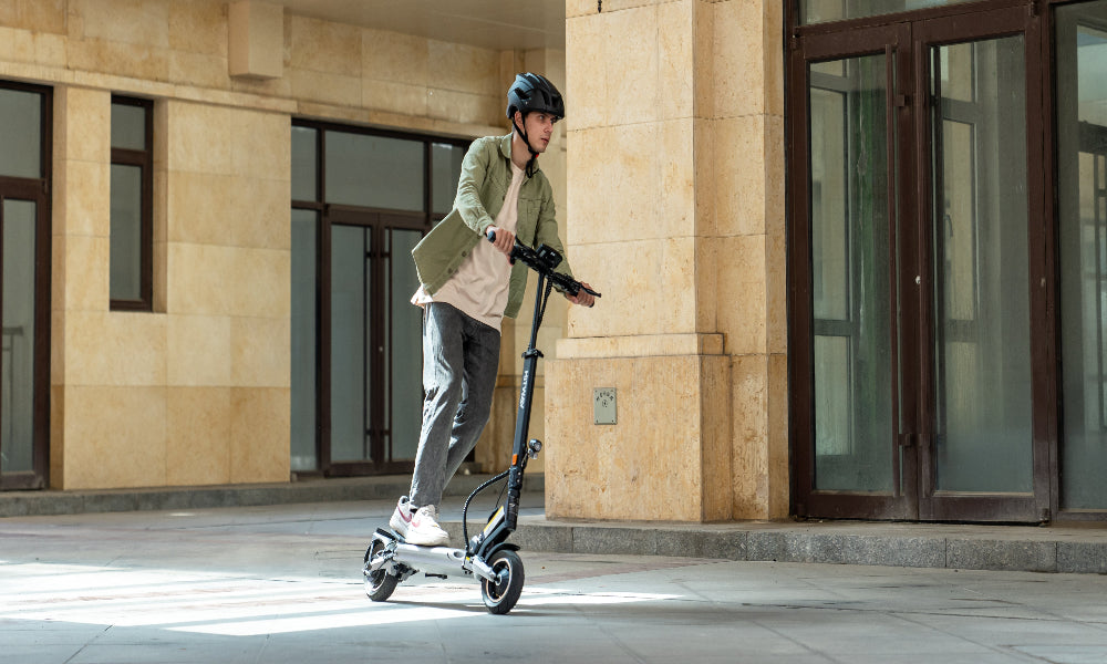 Person using an electric scooter in front of a building
