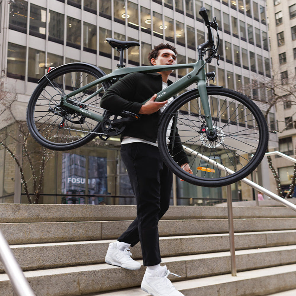 Man draagt een groene fiets een trap op in een stedelijke omgeving