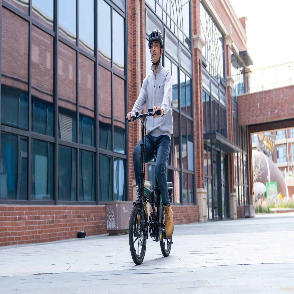 Man riding a bicycle on a city street with modern buildings in the background